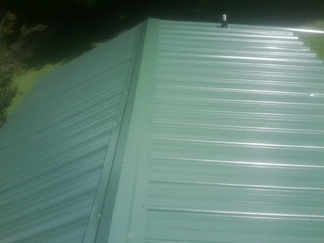 New green metal panels meeting at the ridge of a roof — Flat Roof Repair work by our crew in Daphne