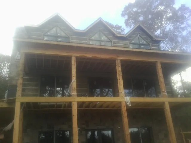 Dormers and porch framing on a large log home under construction — Roof Coating work by our crew in Daphne