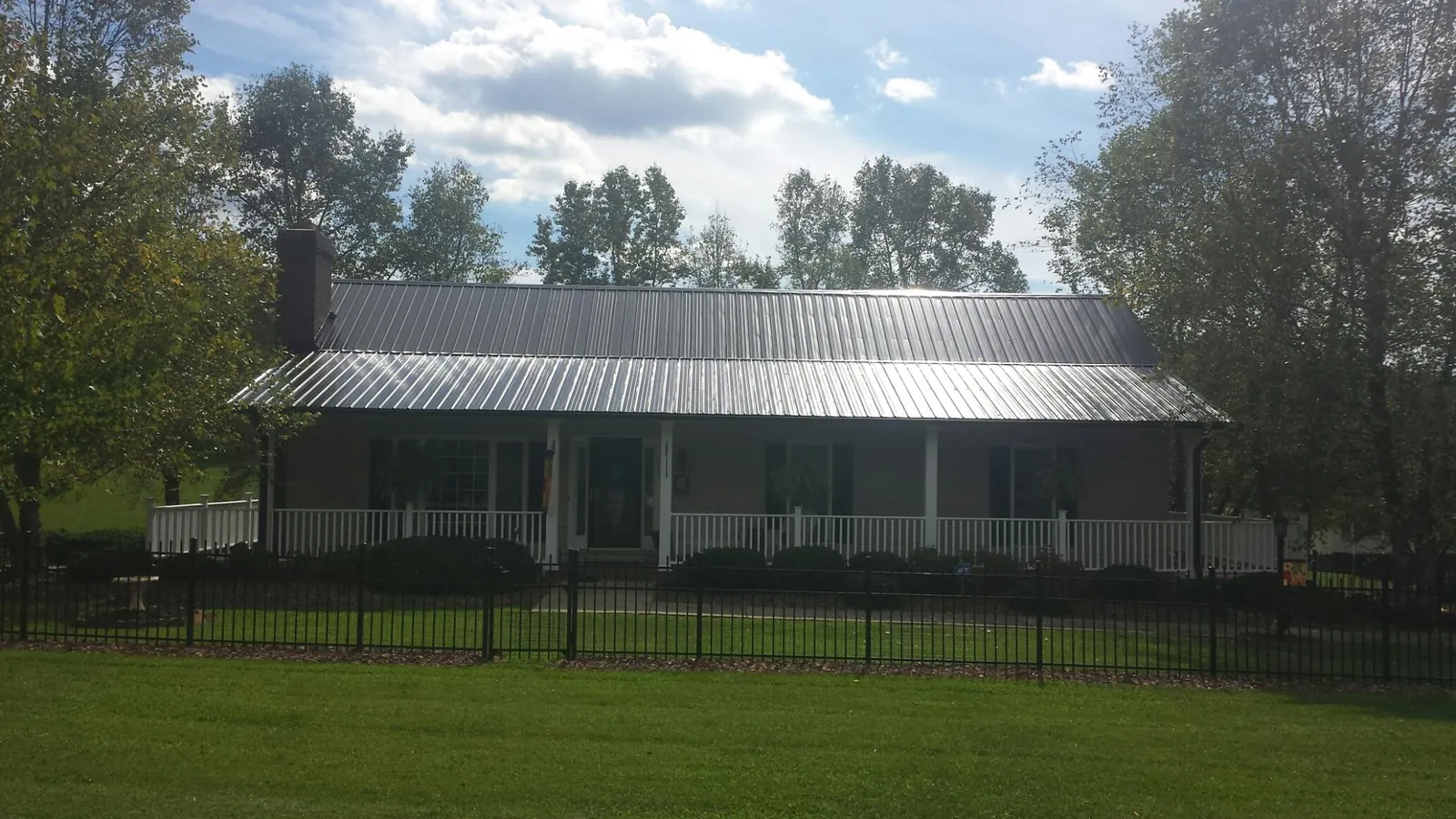 Gray metal roof on a brick ranch with a full width front porch — Gutter Guard Installation work by our crew in Daphne