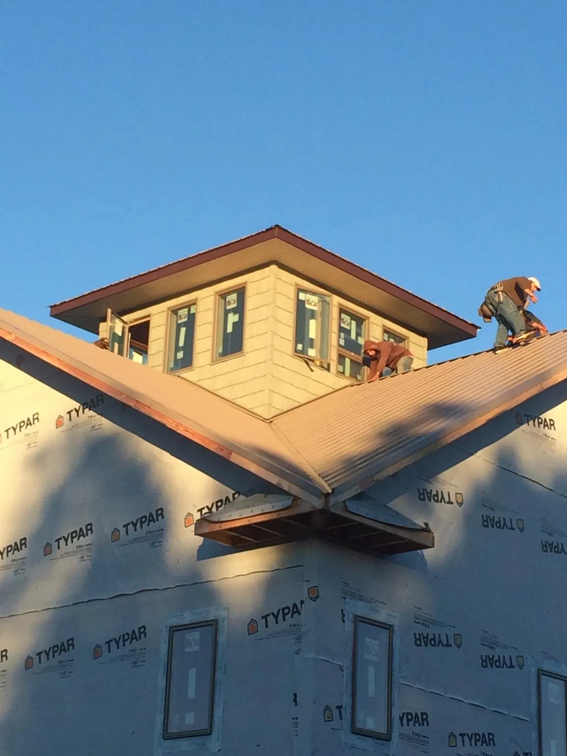 Roofers working around a rooftop cupola on a new metal roof at sunset — Roof Waterproofing in Daphne by Roofing Brothers